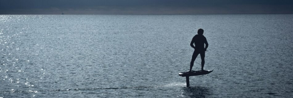 man in black wet suit standing on brown wooden paddle board during daytime