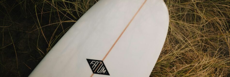 A white surfboard laying in the grass